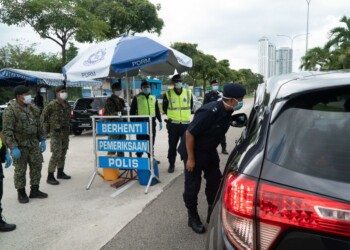 Seri Alam OCPD Supt Ismail Dollah (looking into car window) visiting a roadblock in Seri Alam and conducting checks on drivers to ensure they obey the Movement Control Order.