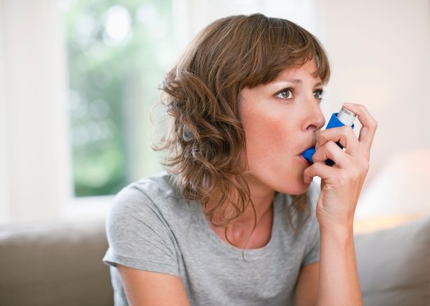 2 Mid adult woman using asthma inhaler